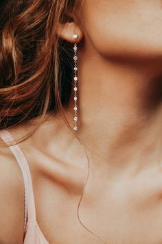 a close up of a woman's face wearing earrings with pearls hanging from them