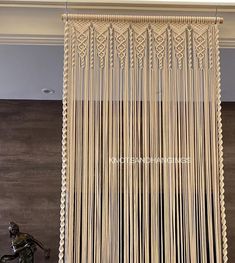 a sculpture sitting in front of a window covered with white string art hanging from it's sides