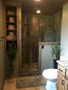 a bathroom with a toilet, sink and shower in it's stall area next to a wooden wall