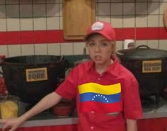 a young boy in a red shirt and cap with the flag of venezuela on it