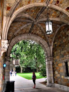 a woman is standing under an arch in the middle of a walkway that leads to a building