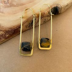 A uniquely fresh and new twist on a modern hoop style earring. We’ve suspended cube gemstones inside the negative space of a rectangle shaped wire hoop. The base of the hoop is hammered flat and tapers up the sides. These earrings are ultra lightweight and very comfortable to wear. ⬩7-9mm x 7-9 mm Cube shape Gemstone ⬩Hoop and Hook style brass wire ⬩2.5 inch Hoop earring ⬩Available in Amazonite, Labradorite, Moonstone, and Tiger Eye This item will ship with gemstone information on the Santore Je Brass Jewelry Handmade, Wild Jewelry, Art Jewelry Earrings, Hammered Jewelry, Jewelry Organizer Wall, Cube Necklace, Cube Shape, Brass Hoop Earrings, Gem Shop