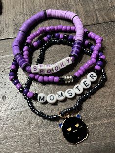 Listing includes stack of 4 Halloween themed bracelets shown in the photo. Bracelet 1 is black and purple Heishi clay beads that says SPOOKY in purple lettering Bracelet 2 is 3mm black and purple seed beads with silver spacers Bracelet 3 is made of black and purple 3mm seed beads that says MOMSTER in black lettering  Bracelet 4 is blackish 2mm seed beads with a gold metal black colored MOMSTER charm Handmade with sturdy, quality elastic These bracelets make PERFECT GIFTS for anyone special!  Siz Handmade Black Heishi Beads Stretch Bracelet, Purple Beaded Bracelets With Black Beads As A Gift, Purple Heishi Beaded Bracelets With Letter Beads, Purple Heishi Beads Bracelet With Letter Beads, Purple Heishi Beads Bracelet With Spacer Beads, Halloween Beaded Bracelet, Purple Gemstone Jewelry, Themed Bracelets, Black Spinel Bracelet