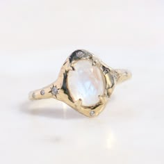 This celestial-inspired piece captures the essence of the goddess of the moon. With its moonstone centerpiece and delicate diamond accents, it carries the serene, otherworldly aura of the night sky. As an engagement ring, it symbolizes the eternal journey of love, akin to the moon's unending phases. Embrace the cosmic sentiment and make it a cherished part of your unique love story. 8x6 mm moonstone, two star set 1.5mm diamonds on each side of the stone, two 1mm diamonds above and below the ston Moonstone And Diamond Ring, Cosmic Engagement Ring, Moon Stone Ring Engagement, Moon Stone Engagement Ring, Moon Wedding Ring, Celestial Engagement Ring, Magical Rings, Star Engagement Ring, Moon Engagement Ring