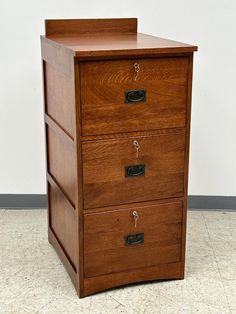 a wooden file cabinet sitting on top of a tile floor next to a white wall