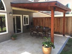 an outdoor patio with table, chairs and potted plants on the side of it