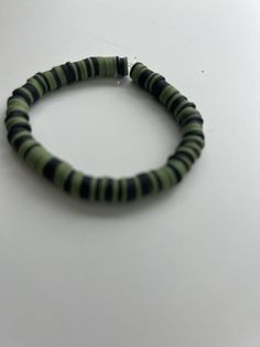 a green and black beaded bracelet sitting on top of a table