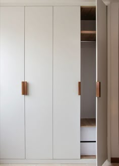 an empty closet with white cupboards and wooden handles