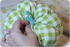 a person is sewing on a green and white checkered pillow