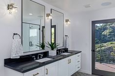 a bathroom with two sinks, mirrors and lights on the wall next to a sliding glass door