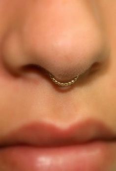 a woman's nose with a gold nose ring on top of her nose and the bottom part of her nose