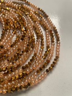 Elastic Waist Bead "Koun-Fao" crafted with resplendent gold glass crystal seed beads and adorned with delicate light brown glass seed bead accents. This elastic waist bead not only emanates opulence but also embodies a warm and earthy elegance, offering a comfortable and adjustable fit that transcends beauty and symbolism. 🌟 Gold Glass Crystal Seed Beads - Opulent Radiance: Koun-Fao is adorned with a luxurious array of gold glass crystal seed beads, creating an opulent radiance that symbolizes Gold Multi-strand Beaded Bracelet, Festive Gold Beaded Bracelets, Gold Beaded Bracelets For Party With Round Beads, Elegant Gold Polished Waist Beads, Festive Gold Beaded Bracelets With Round Beads, Bohemian Beaded Waist Beads For Parties, Handmade Multi-strand Gold Beaded Bracelets, Gold Round Waist Beads For Gifts, Gold Beaded Bracelet With Colorful Beads For Festivals