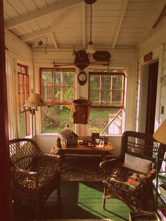 the sun shines in through two windows onto an enclosed porch with wicker furniture