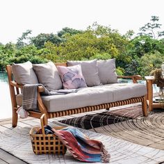 a couch sitting on top of a wooden floor next to a basket filled with pillows