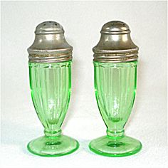 two green glass vases sitting next to each other on top of a white surface