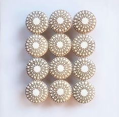 twelve white decorated donuts arranged in the shape of a pyramid on a white surface