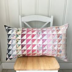 a pillow sitting on top of a wooden table next to a white chair and wall