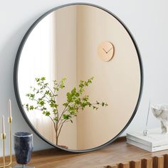 a round mirror sitting on top of a wooden table next to a vase with a plant in it