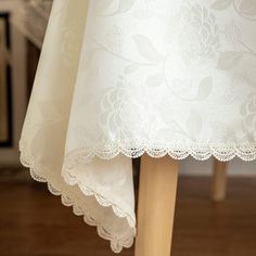 the table cloth is white and has flowers on it, along with two wooden legs