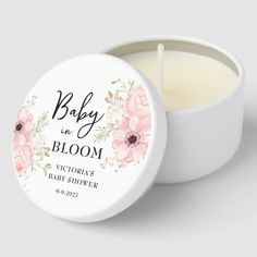 a white candle with pink flowers on it and the words baby in bloom written above