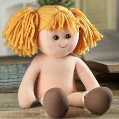 a stuffed doll with yellow hair sitting on the floor