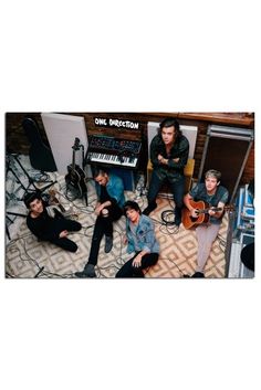 a group of people sitting on top of a floor next to musical instruments and keyboards