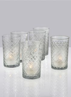 four clear glass tumblers with candles in them