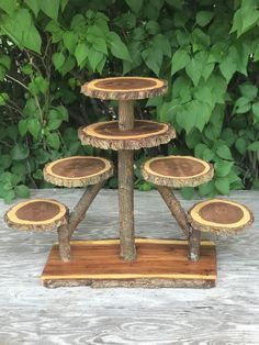 three tiered tree slice cake stand in front of some trees