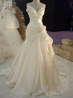 a white wedding dress on display at a bridal event with other gowns in the background