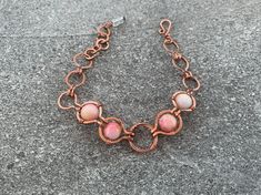 The Pink Nest Bracelet features polished agate stones in rich pink and cream hues with flecks of yellow and orange, wrapped in high-quality pure copper.  Flaunt this modern, art-deco-inspired look with a sophisticated feel to compliment your style and elevate any outfit. Give as a memorable unique gift to the favorite woman in your life: For Mother's Day, anniversary presents, Christmas gifts, birthday gifts, graduation and bachelorette parties. ## Sizing Total length is 7.5 inches. ## Materials Every item is 100% handmade and one-of-a-kind. The wire-wrapped raw copper jewelry is oxidized and polished to beautifully highlight details of the wirework. Finally, it's sealed with a protective clear coat to prevent tarnishing and allergic reactions. Since gemstones are unique, a slight variatio Bohemian Pink Agate Bracelets, Pink Wire Wrapped Copper Jewelry, Handmade Pink Copper Wire Jewelry, Adjustable Unique Rose Quartz Jewelry, Pink Wire Wrapped Copper Wire Jewelry, Pink Copper Wire Jewelry For Gifts, Pink Copper Wire Wrapped Jewelry, Pink Hand Wrapped Round Beads Jewelry, Pink Hand-wrapped Bangle Jewelry