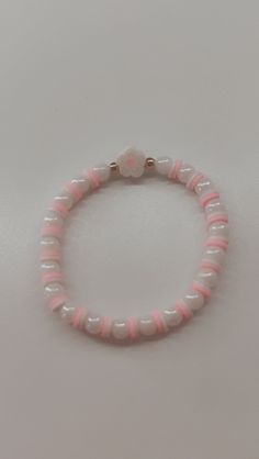 a pink and white beaded bracelet sitting on top of a table