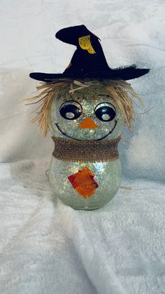 a glass snowman with a black hat and orange fish on it's head