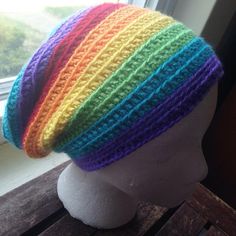 a white mannequin head wearing a multicolored knitted hat