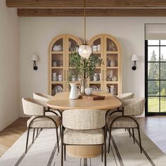 the dining room table is surrounded by beige chairs and an arched glass door that leads to a patio