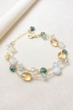 This artisan-crafted, multi-gemstone style bracelet boasts striking green gems, including aquamarine and moss agate, paired perfectly with lustrous golden quartz gems.  Rainbow moonstone adds an ethereal glow.

This is a timeless accessory perfect for weddings and other special occasions, as well as elevating your everyday style.

Handcrafted in southeastern Georgia. Making Crystal Bracelets, Gold Bracelets With Natural Stones And Mineral Crystal, Green Bracelets With Gemstone Accents As Gift, Green Citrine Jewelry With Gemstone Accents, Green Gemstone Bracelet Jewelry, Green Gemstone Accented Bracelet, Green Gemstone Accents Bracelet, Green Gemstone Accent Bracelet, Green Citrine Jewelry With Natural Stones