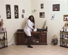 a woman in a room with many pictures on the wall and decorations all around her