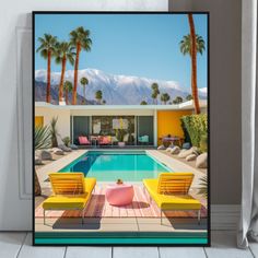 a framed photograph of a pool with chairs and palm trees