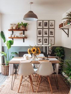 a dining room table with white chairs and sunflowers on the table in front of it