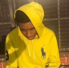 a man in a yellow hoodie looking at his cell phone