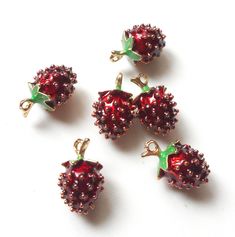 four red jeweled cherries with green leaves on them sitting next to each other