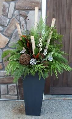 a blue vase filled with lots of greenery and pine cones on top of a table