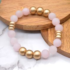 Dreamy rose quartz and golden wood beads make up our newest gemstone bracelet! The gorgeous pale pink rose quartz gemstones in this bracelet are matte and perfectly contrast the super shiny golden wood beads in this design. Rose Quartz is said to be a fantastic stone to wear for promoting self-love, fostering positive relationships, and attracting love and compassion. Get this bracelet for yourself or for a friend and adorn yourself with Dreamy Rose Quartz! Rose Quartz is a form of quartz that i Gold Rose Quartz Beaded Bracelets, Gold Rose Quartz Beaded Bracelets With Round Beads, Gold Beaded Bracelet With Rose Quartz Round Beads, Gold Beaded Bracelets With Rose Quartz Round Beads, Gold Beaded Bracelets With Rose Quartz, Spiritual Gold Beaded Rose Quartz Bracelets, Internal Healing, Loved And Lost, Attracting Love