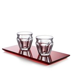 two shot glasses sitting on top of a red glass tray with the bottom half empty