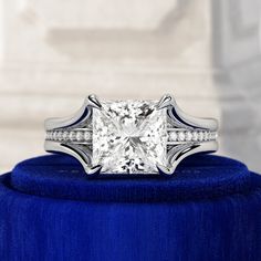 a princess cut diamond ring on top of a blue velvet box