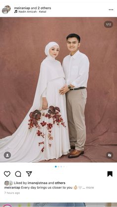 a man and woman standing next to each other in front of a brown backdrop with flowers