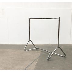 a pair of metal stands sitting on top of cement floor next to a white wall