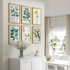 a dining room with white furniture and paintings on the wall