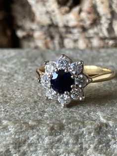 A wonderful vintage 18ct Gold Natural Sapphire And Diamond Cluster ring , eight gorgeous bright sparkling Brilliant Cut Diamonds approximately 2.5mm, totalling approximately 50pts or half a carat surrounding a stunning deep blue Sapphire 5mm in diameter approximately 65pts or over half a carat ,  classic flower design cluster, hallmarked in London 1986, Size l or US 5.5 Dazzling Yellow Gold Sapphire Ring With Brilliant Cut, Dazzling Yellow Gold Sapphire Ring, Classic Cluster Sapphire Diamond Ring, Classic Sapphire Cluster Diamond Ring, Classic Cluster Promise Ring, Yellow Gold Cluster Sapphire Ring With Brilliant Cut, Yellow Gold Sapphire Cluster Ring With Brilliant Cut, Yellow Gold Cluster Sapphire Ring With Center Stone, Yellow Gold Sapphire Cluster Ring With Center Stone