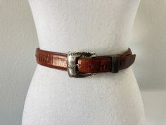 This has great detail and is a burnished chestnut leather. *For Belts: Measurements to first and last holes = measuring from the prong. I will share damage to the underside of the belt if it may interfere with the integrity of the belt. I always show on a female dress form regardless of the type of belt. Video will show belt end to end. Description: Onyx size 36 dark chestnut leather tarnished buckle buckle stamped 1993 Vintage: 1993 Condition: very good does show signs of wear please see all photos/video Measurements: approx 34.75" to last hole approx 37.75" to first hole approx 1.25" wide buckle approx 2" x 2"  The Fine Print: I provide  very detailed descriptions, measurements and photos. If you have a question, please ask. I will do my best to answer and give you peace of mind that you Classic Hand Tooled Brown Belt Buckles, Classic Brown Hand Tooled Belt Buckles, Western Brown Belt For Formal Occasion, Western Style Brown Belt For Formal Occasions, Formal Brown Concho Belt Buckles, Classic Brown Belt With Concho Details, Chestnut Leather, Female Dress, Belt Vintage