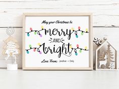 merry and brights printable christmas card with string lights on white wooden table next to small house